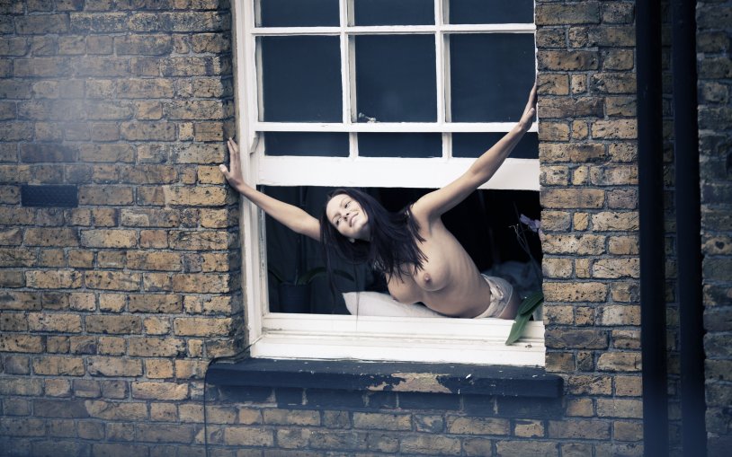 The girl undresses in the window