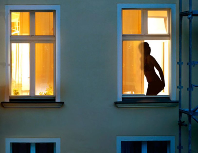 The girl undresses in the window
