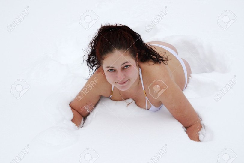 Girl lies in the snow in a swimsuit