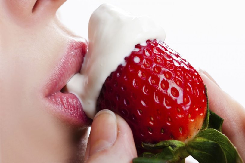 The girl eats strawberries with cream