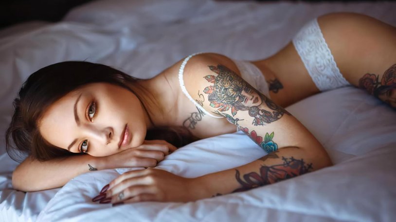 The girl lies in white underwear and in tattoos