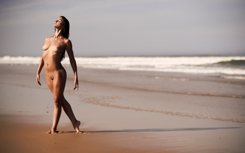 Naked women run along the beach
